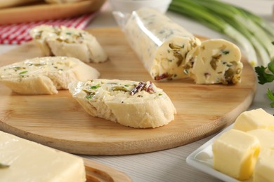 Photo of Tasty butter with olives, green onion and bread on wooden table, closeup