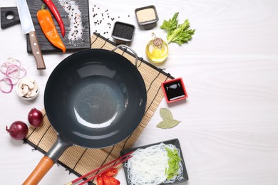 Photo of Wok, chopsticks and different products on white wooden table, flat lay. Space for text