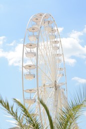 Photo of Large white observation wheel against blue cloudy sky