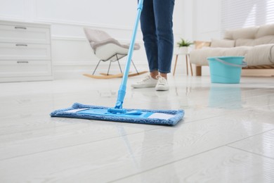 Photo of Woman cleaning parquet floor with mop at home, closeup