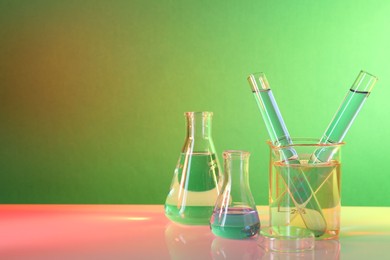 Photo of Laboratory analysis. Different glassware on table against color background, space for text