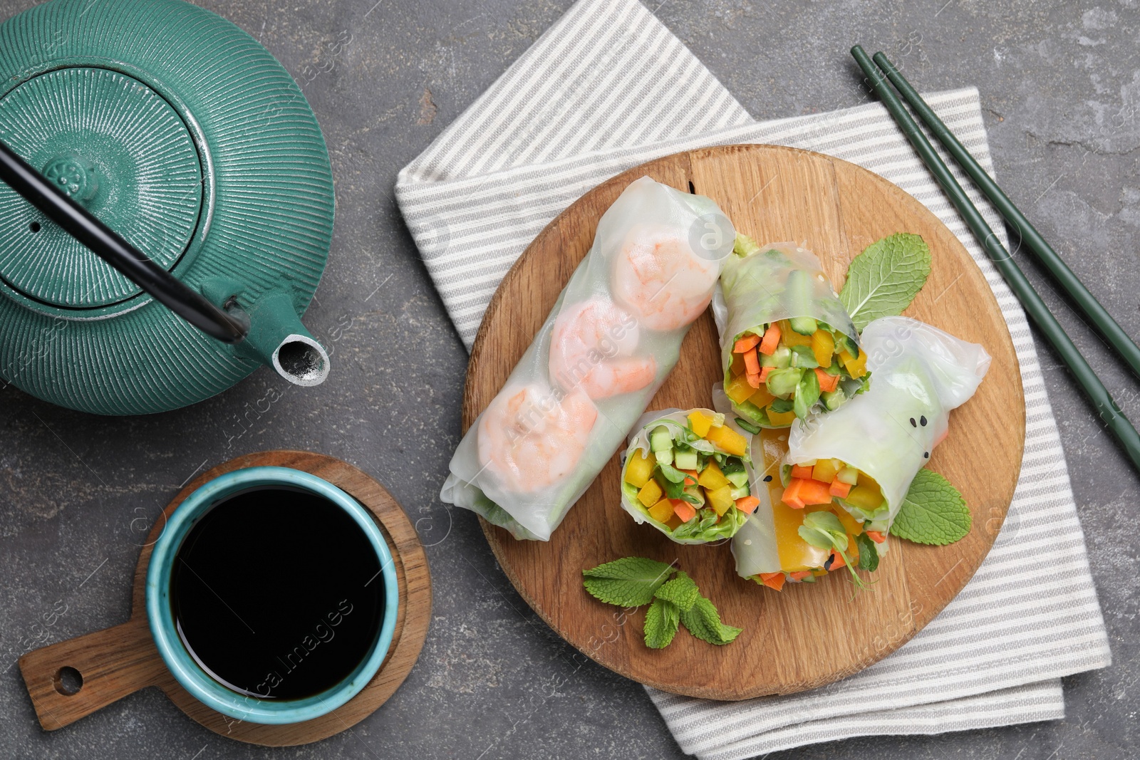 Photo of Tasty spring rolls served on grey textured table, flat lay