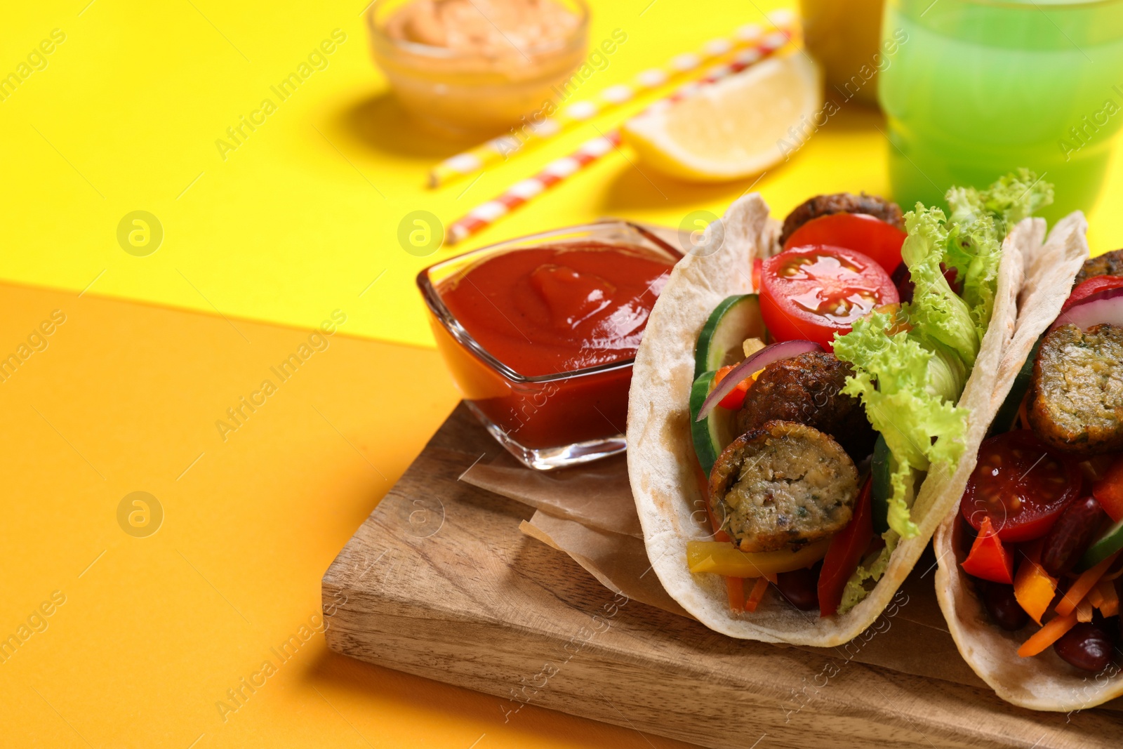 Photo of Delicious tacos served on yellow table, closeup. Space for text