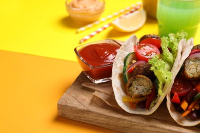 Photo of Delicious tacos served on yellow table, closeup. Space for text