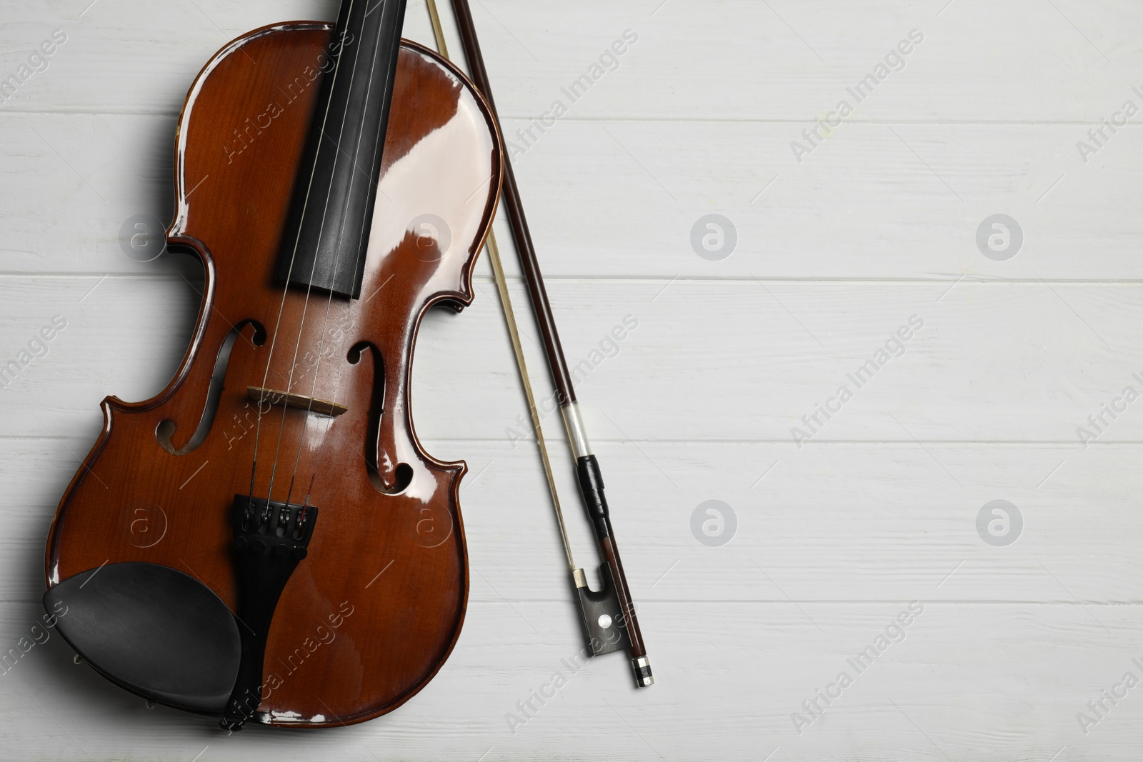 Photo of Classic violin and bow on white wooden background, flat lay. Space for text