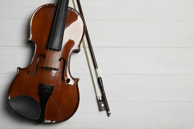 Photo of Classic violin and bow on white wooden background, flat lay. Space for text