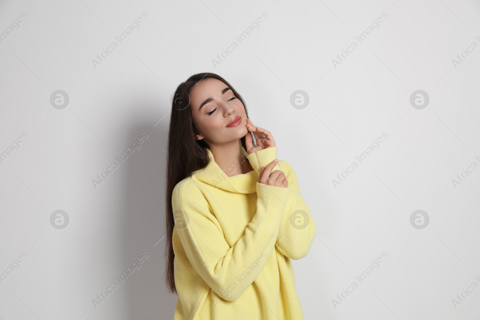 Photo of Beautiful young woman wearing yellow warm sweater on white background