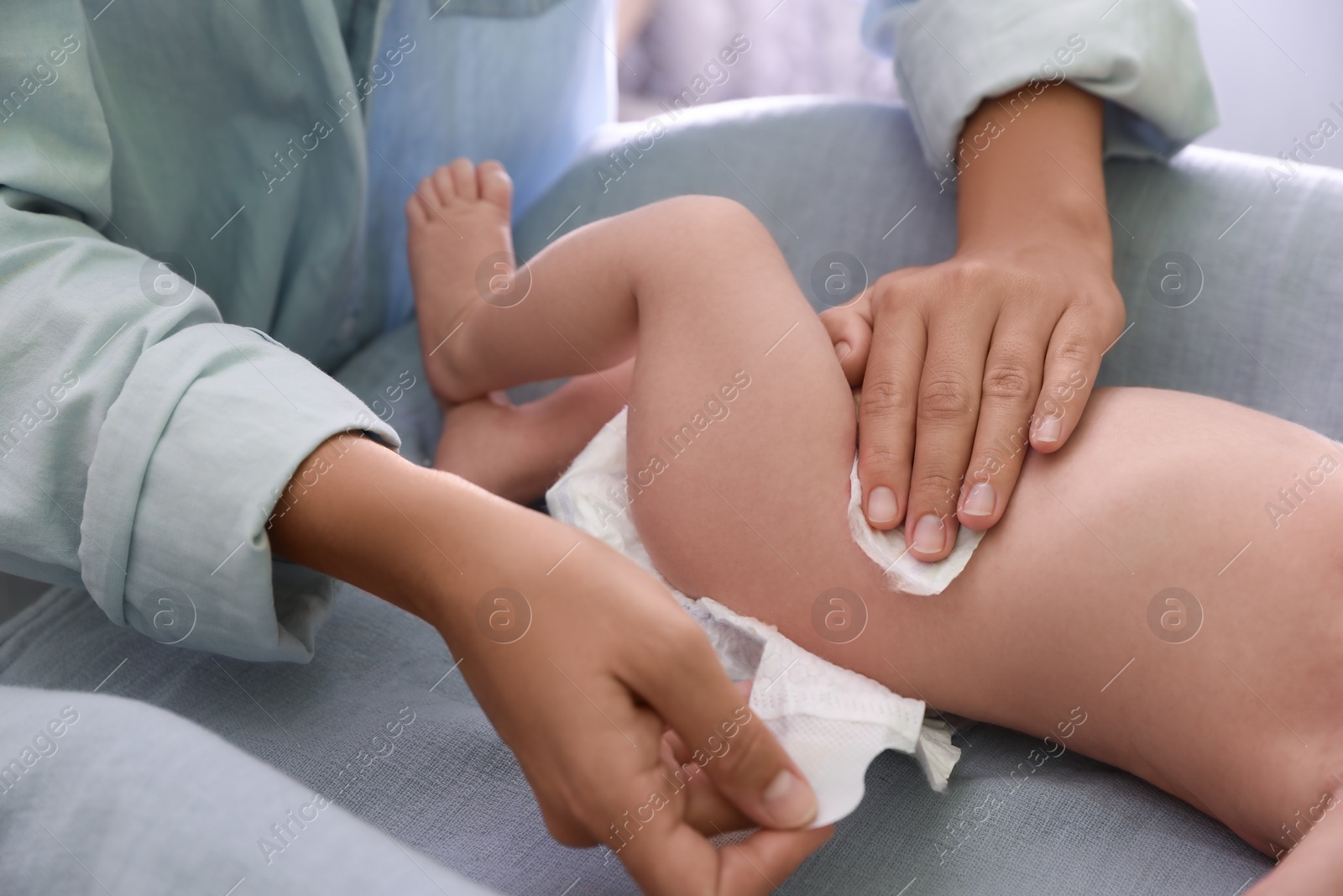 Photo of Mother changing baby's diaper on table indoors, closeup