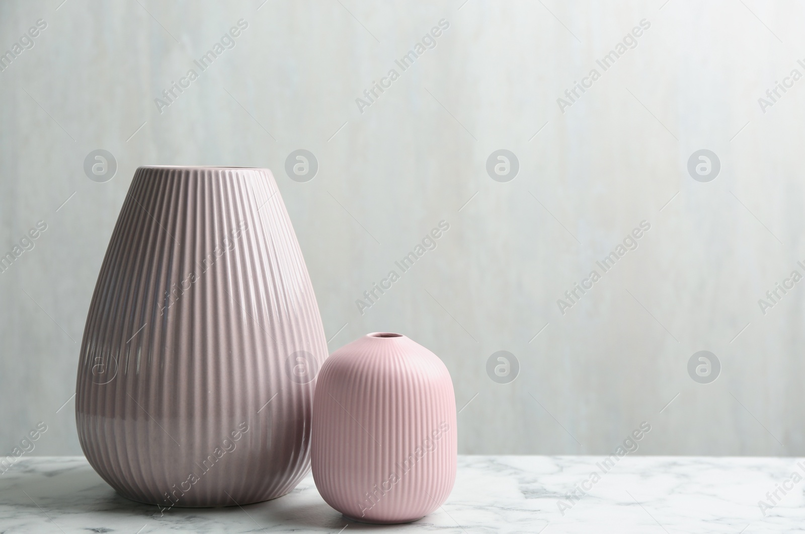 Photo of Stylish pink ceramic vases on white marble table, space for text