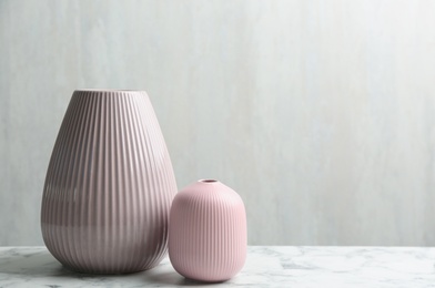 Photo of Stylish pink ceramic vases on white marble table, space for text
