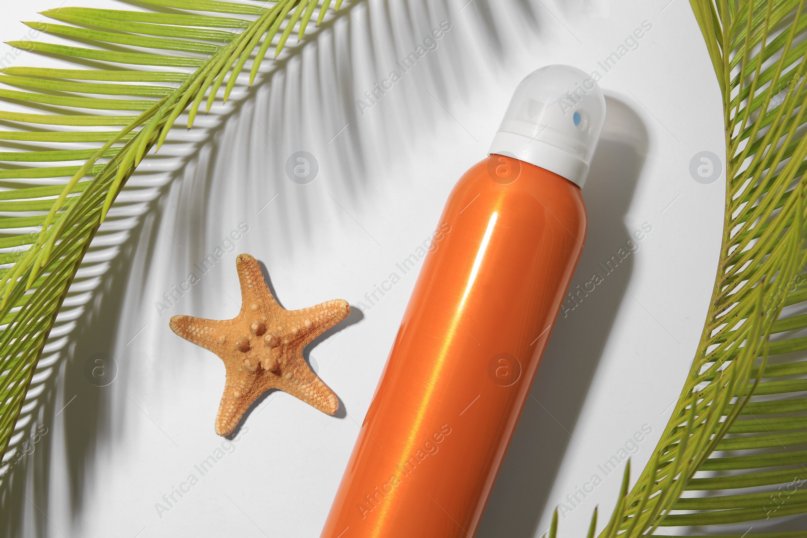 Photo of Sunscreen, starfish and tropical leaves on white background, flat lay. Sun protection care