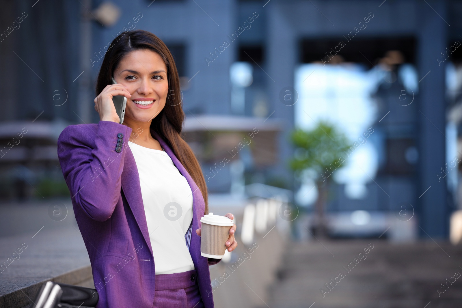 Photo of Beautiful businesswoman with cup of coffee talking on phone outdoors. Space for text