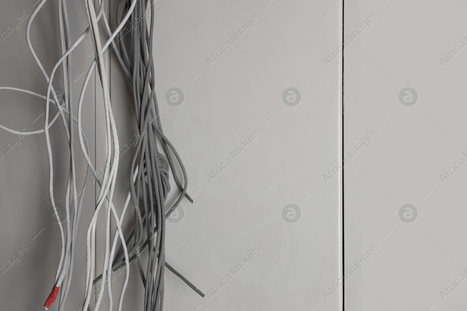 Photo of Different cables on white wall indoors. Installation of electrical wiring