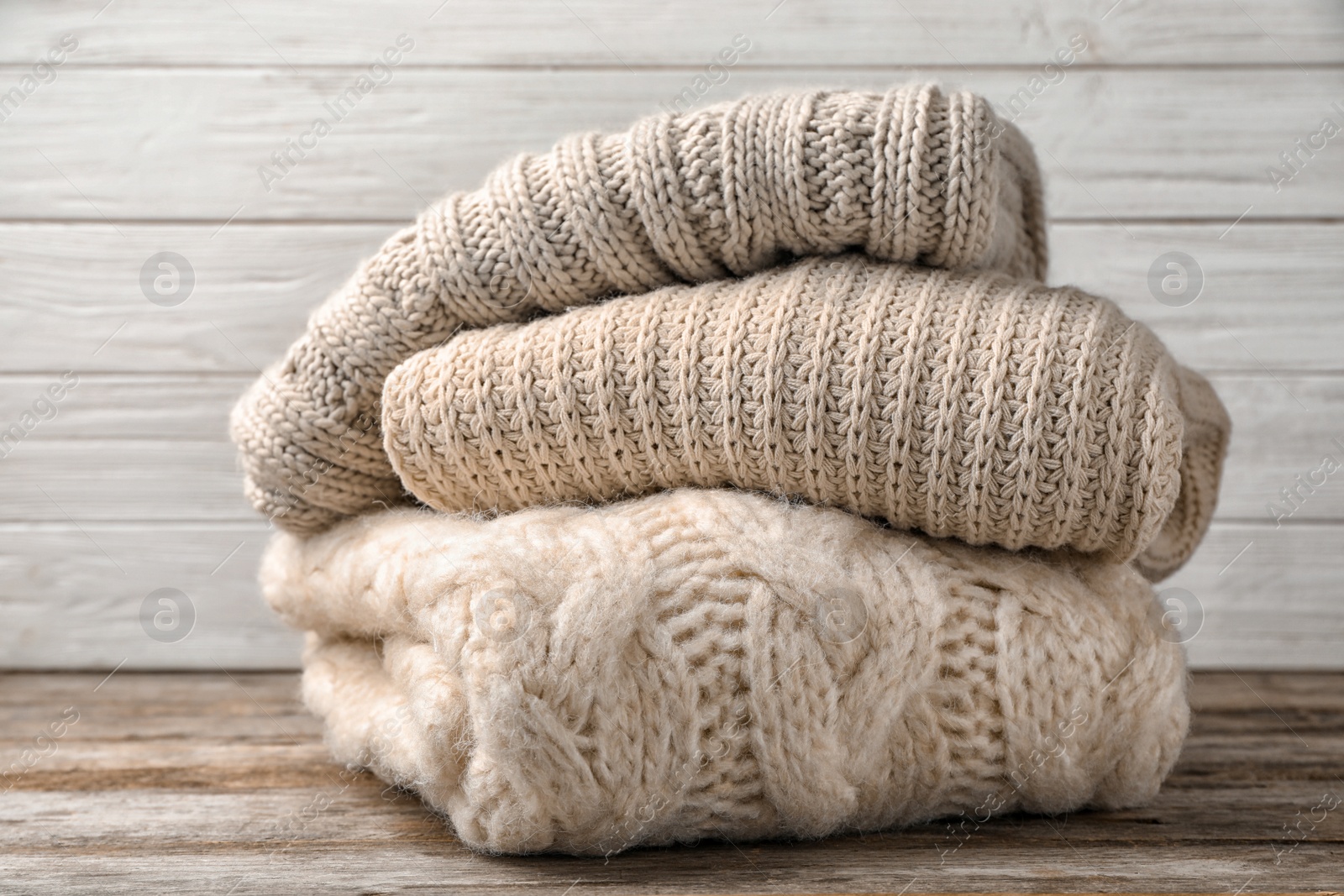 Photo of Stack of folded knitted sweaters on table