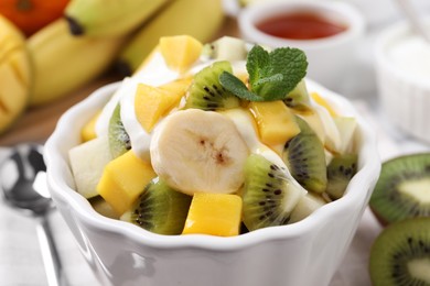 Photo of Delicious fruit salad with yogurt in bowl, closeup