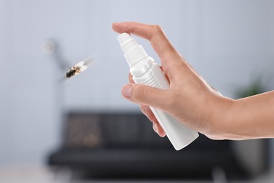 Woman using fly spray in room, closeup