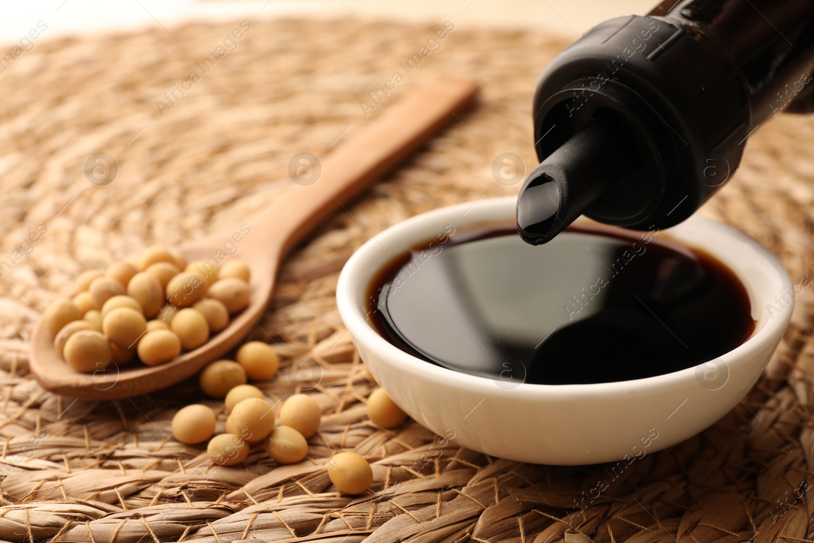 Photo of Holding bottle above bowl with soy sauce, closeup