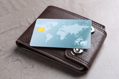 Photo of Credit card and leather wallet on grey textured table, closeup
