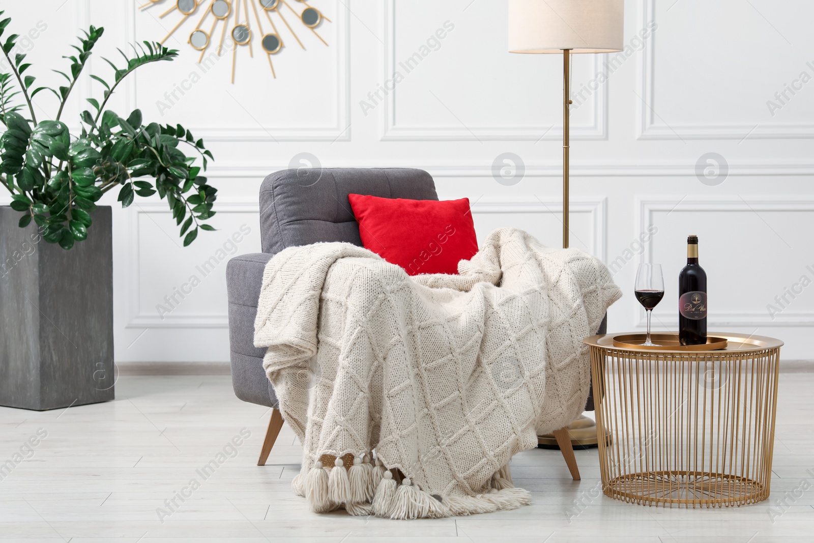 Photo of Stylish living room interior with comfortable armchair, blanket, side table and houseplant