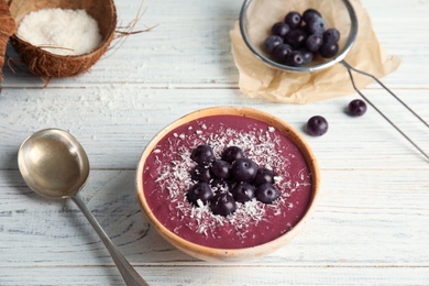 Photo of Bowl with tasty acai smoothie on wooden table