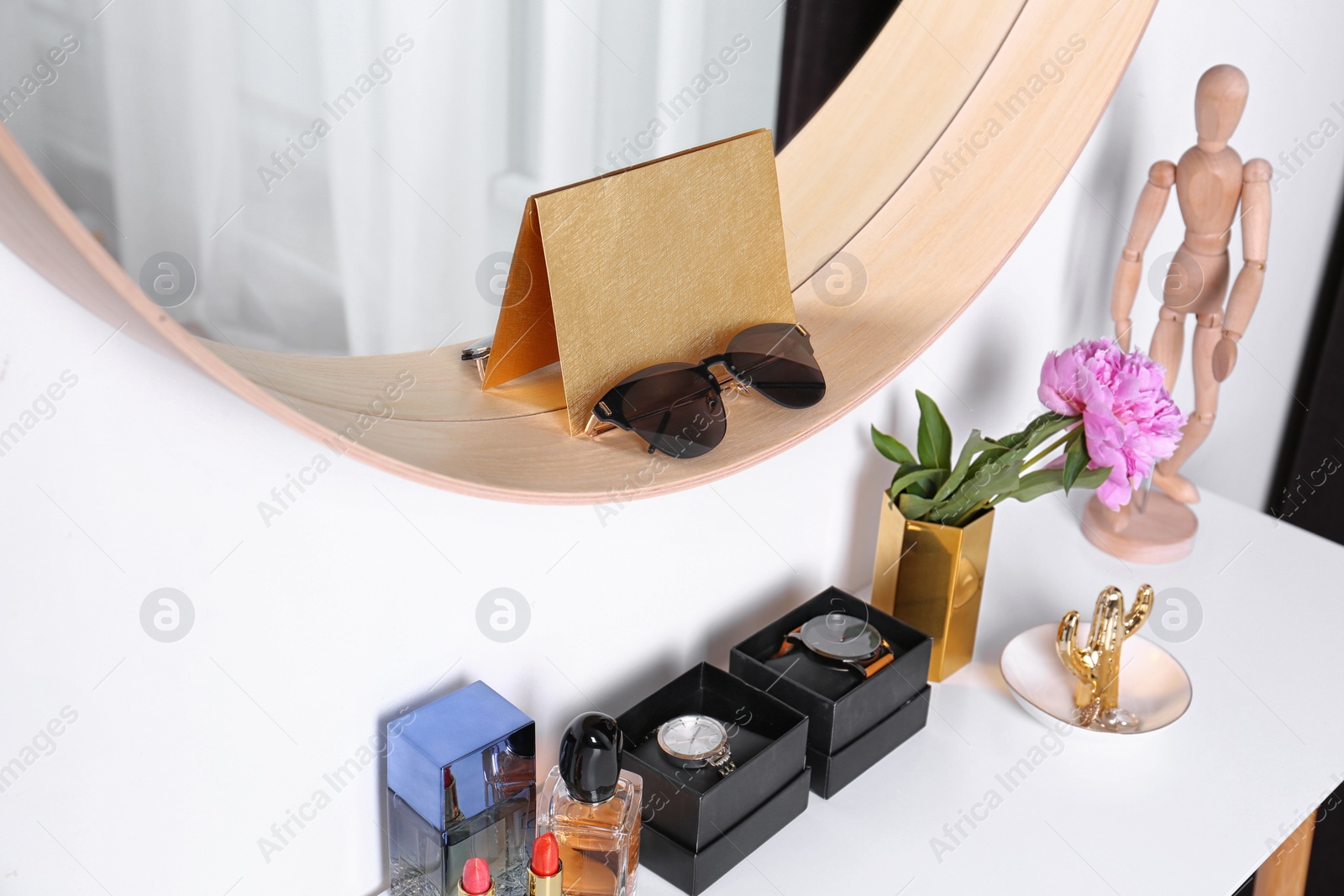 Photo of Stylish round mirror and dressing table with accessories indoors. Interior design