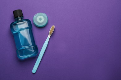 Photo of Mouthwash, toothbrush and dental floss  on purple background, flat lay. Space for text