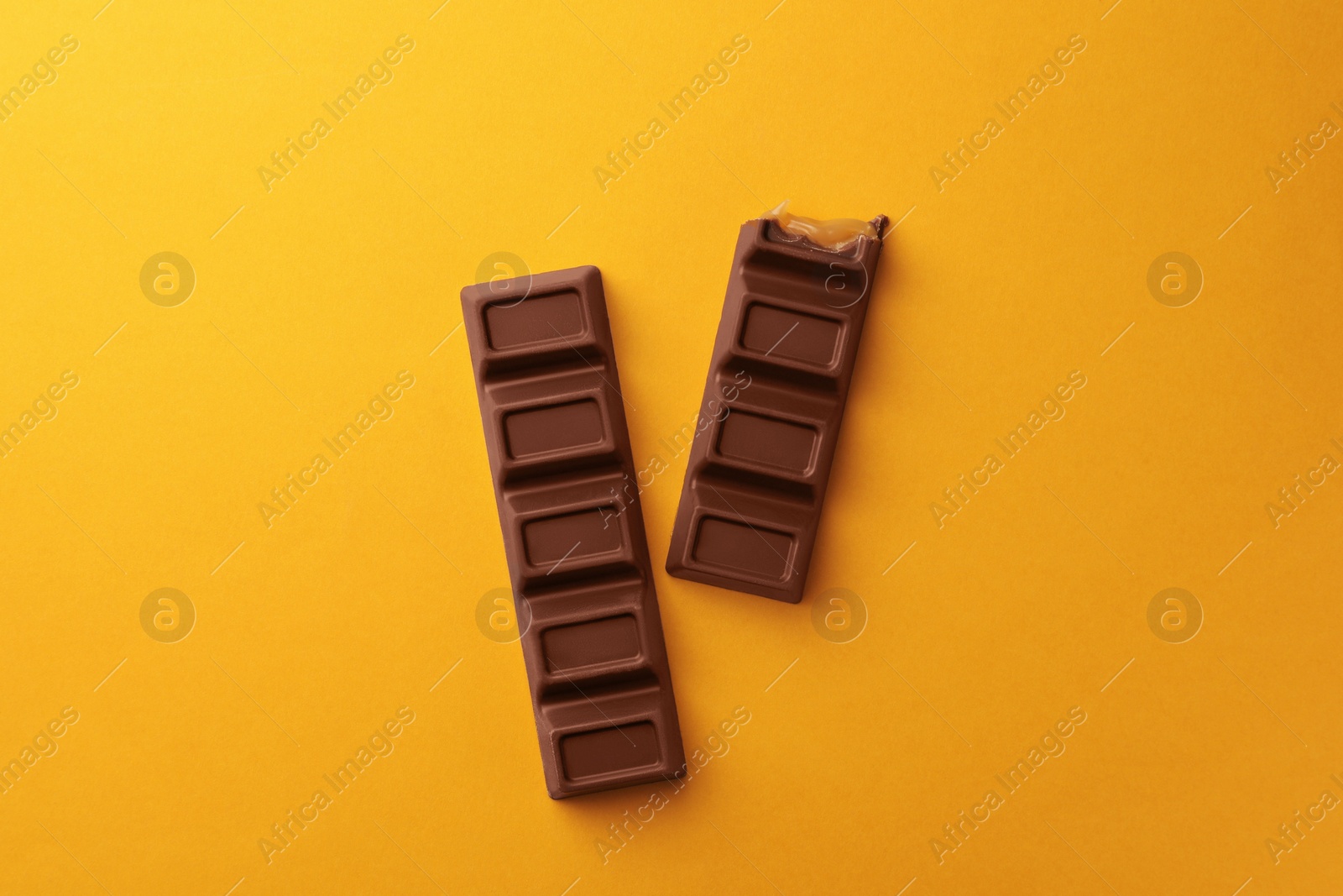 Photo of Tasty chocolate bars on yellow background, flat lay