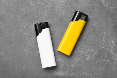 Photo of Stylish small pocket lighters on grey table, flat lay