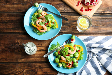 Photo of Tasty salad with Brussels sprouts served on wooden table, flat lay