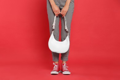 Woman with stylish bag on red background, closeup