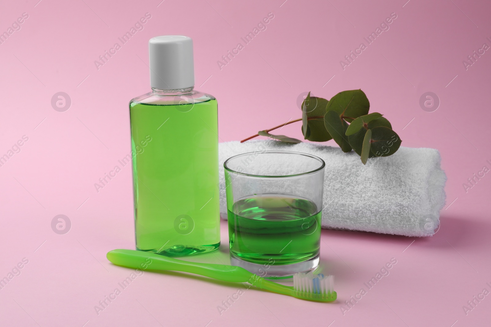 Photo of Composition with fresh mouthwash in bottle, glass and toothbrush on pink background, closeup