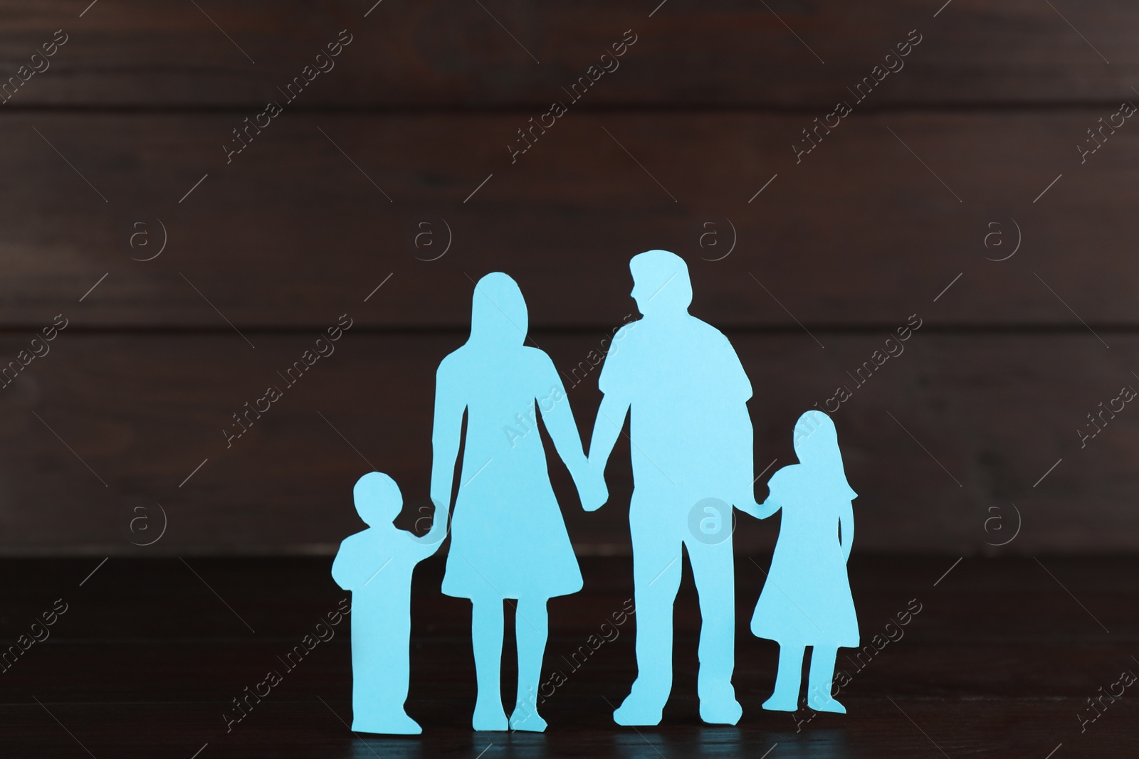 Photo of Paper family figure on wooden table. Child adoption concept