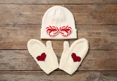 Photo of Warm knitted hat and mittens on wooden background, flat lay