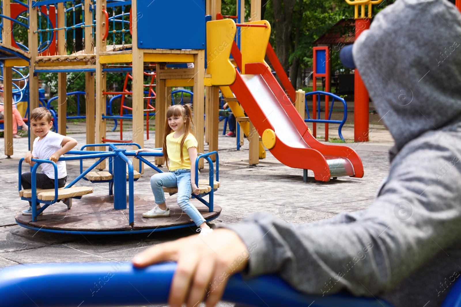 Photo of Suspicious adult man spying on kids at playground, space for text. Child in danger