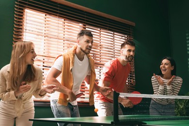 Happy friends playing ping pong together indoors