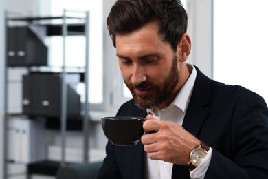 Photo of Handsome bearded man drinking cup of coffee indoors