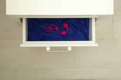 Photo of Pink anal balls in drawer indoors, top view. Sex toy