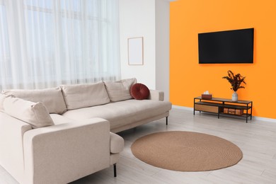 Stylish sofa near orange wall in room. Interior design