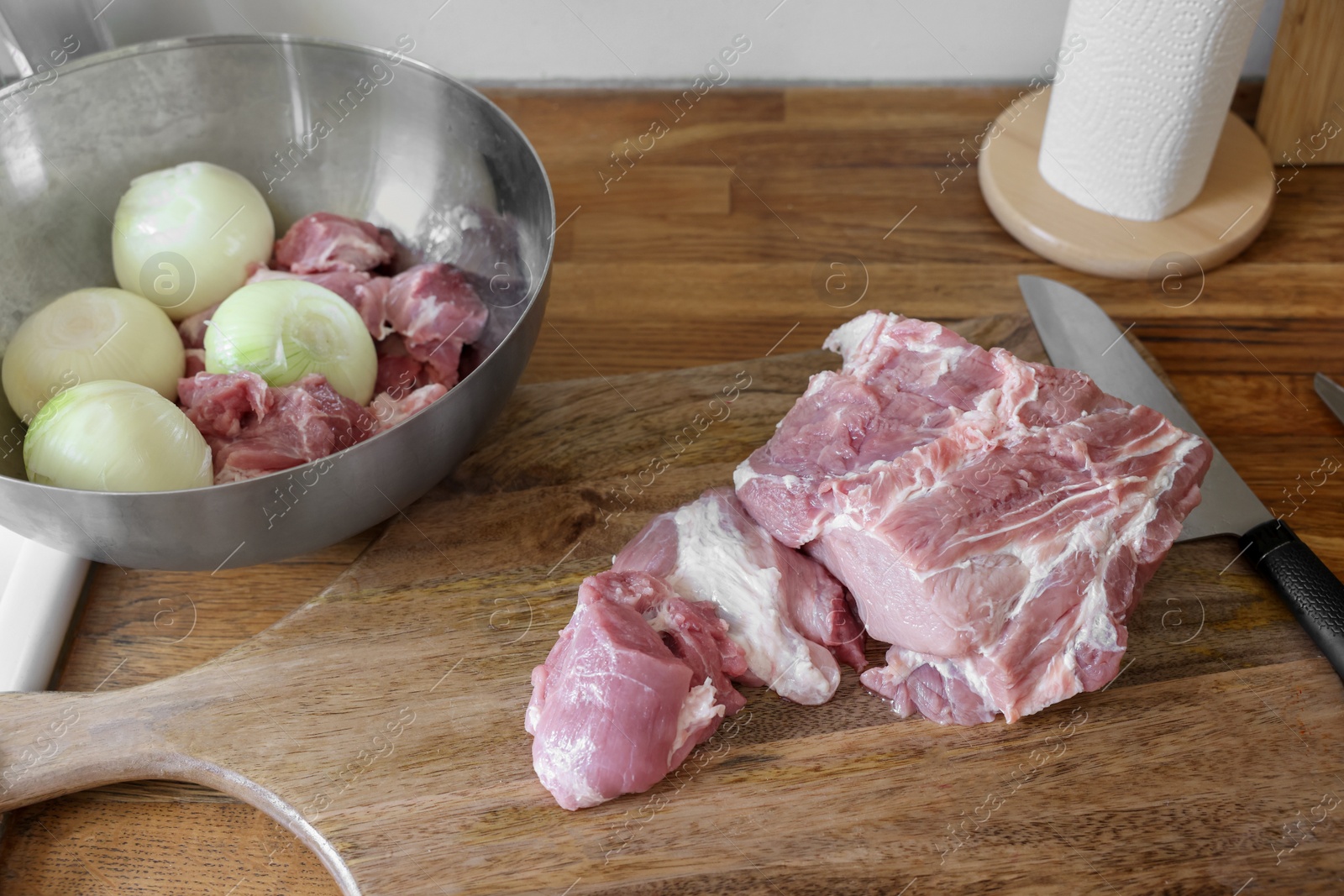 Photo of Fresh raw meat and ripe onions on wooden table