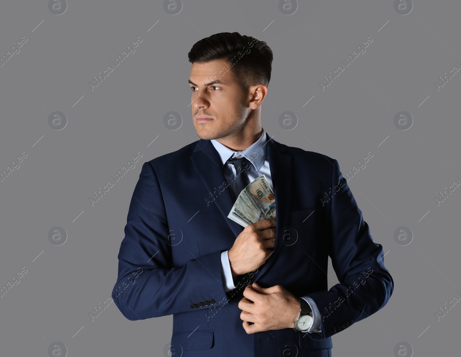 Photo of Man putting bribe into pocket on grey background