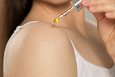 Woman applying essential oil onto shoulder, closeup