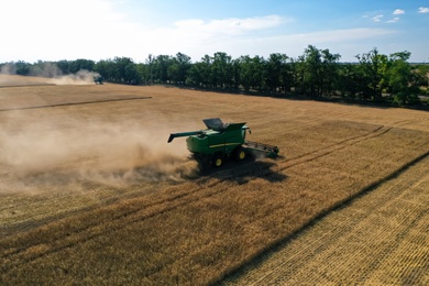 Photo of Modern combine harvester working in field on sunny day. Agriculture industry