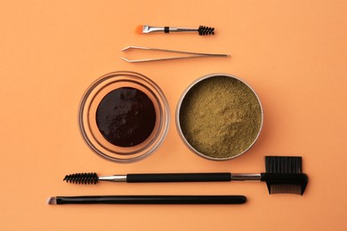 Photo of Flat lay composition with eyebrow henna and professional tools on orange background