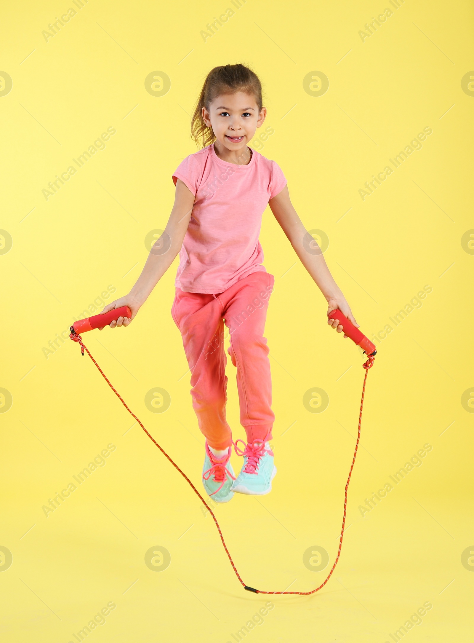 Photo of Full length portrait of girl jumping rope on color background