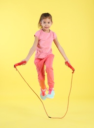 Photo of Full length portrait of girl jumping rope on color background