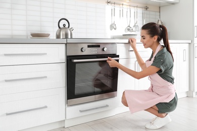 Young woman baking something in oven at home