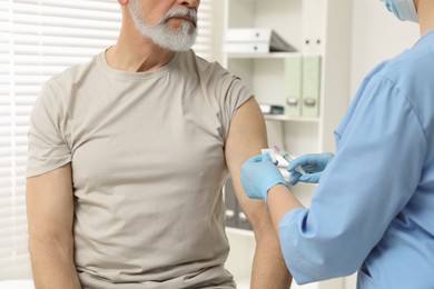 Photo of Doctor giving hepatitis vaccine to patient in clinic, closeup