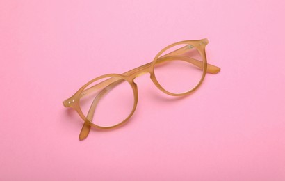 Photo of Glasses with corrective lenses on pink background, top view