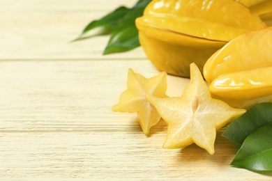Delicious carambola fruits on yellow wooden table. Space for text