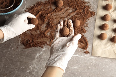 Woman preparing tasty chocolate truffles at table, top view